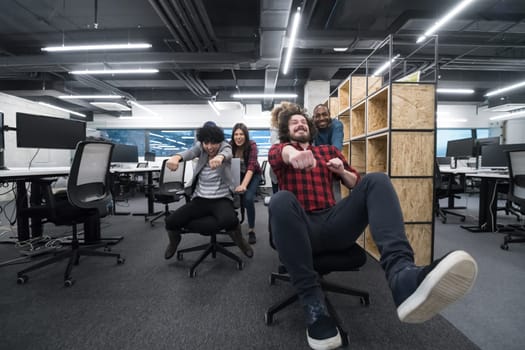 multiethnics startup business team of software developers having fun while racing on office chairs,excited diverse employees laughing enjoying funny activity at work break, creative friendly workers playing game together