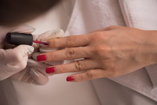 Woman hands receiving a manicure in beauty salon. Nail filing. Close up, selective focus.