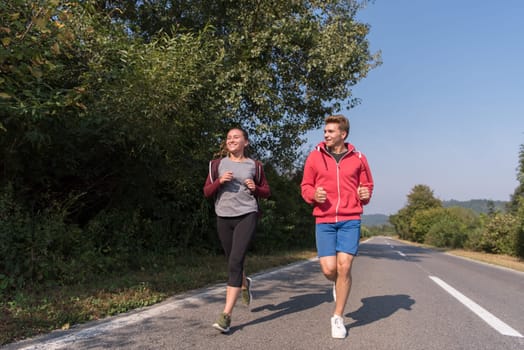 young couple enjoying in a healthy lifestyle while jogging along a country road, exercise and fitness concept
