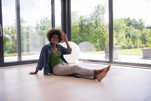 Beautiful african american young woman in casual fashion clothes sitting near window