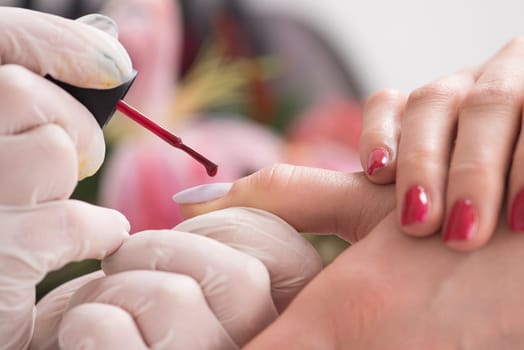 Woman hands receiving a manicure in beauty salon. Nail filing. Close up, selective focus.