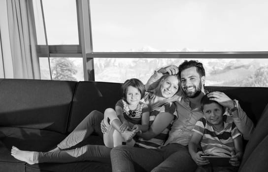 happy couple spending time with kids using tablet computer on sofa at home