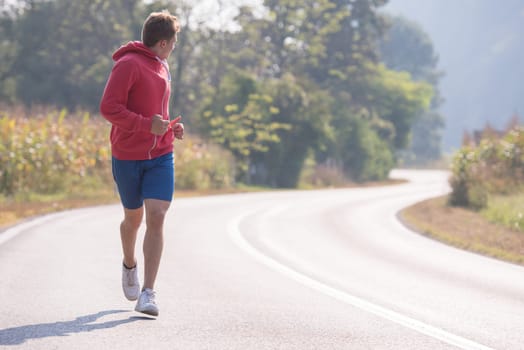 young man enjoying in a healthy lifestyle while jogging along a country road, exercise and fitness concept