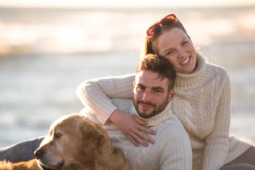 Couple With A Dog enjoying time  together On The Beach at autumn day
