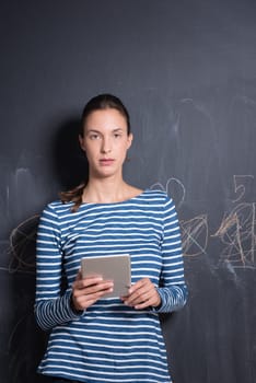 Happy young woman using tablet computer in front of chalk drawing board