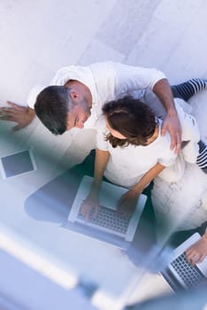 top view of a young couple relaxing at home with tablet and laptop computers reading on the floor