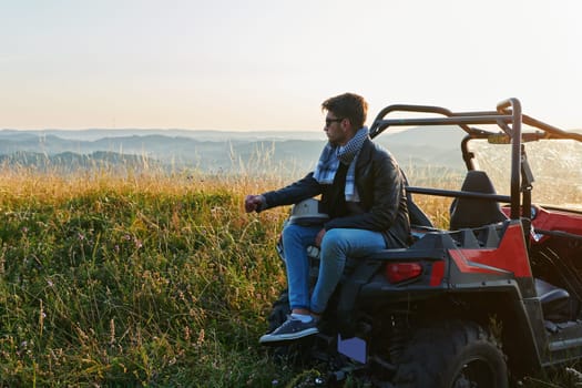 portrait of young happy excited man enjoying beautiful sunny day while driving a off road buggy car on mountain nature