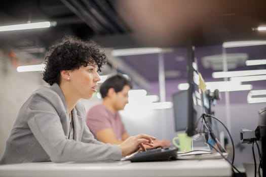 young female software developer using desktop computer while writing programming code at modern creative startup office