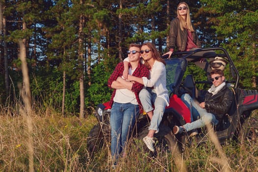 portrait of group young happy people enjoying beautiful sunny day while driving a off road buggy car on mountain nature