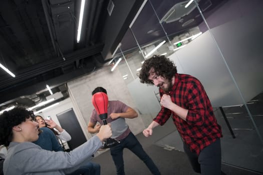 multiethnics startup business team of software developers having fun while boxing at office,excited diverse employees laughing enjoying funny activity at work break, creative friendly workers playing game together