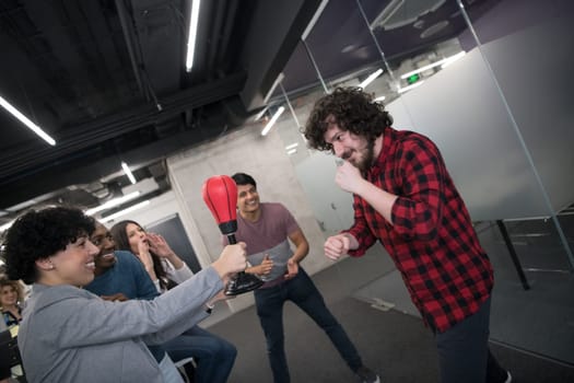 multiethnics startup business team of software developers having fun while boxing at office,excited diverse employees laughing enjoying funny activity at work break, creative friendly workers playing game together