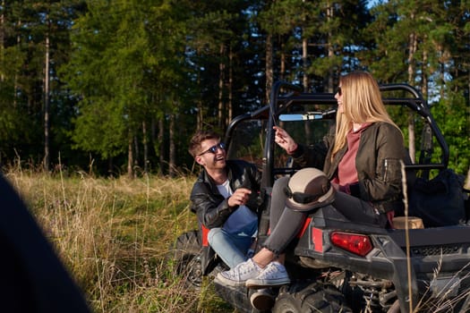 portrait of young happy excited couple enjoying beautiful sunny day while driving a off road buggy car on mountain nature