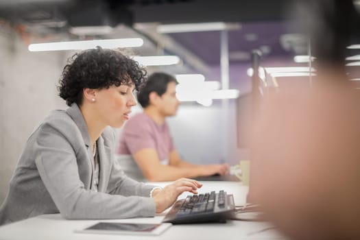 young female software developer using desktop computer while writing programming code at modern creative startup office
