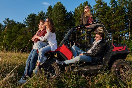 portrait of group young happy people enjoying beautiful sunny day while driving a off road buggy car on mountain nature