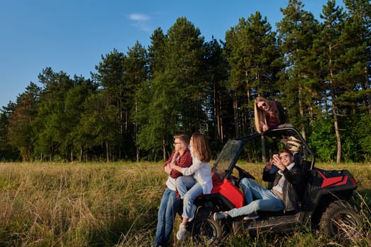 portrait of group young happy people enjoying beautiful sunny day while driving a off road buggy car on mountain nature