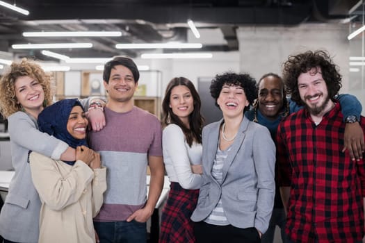 portrait of young excited multiethnics business team of software developers standing and looking at camera while celebrating success at modern startup office