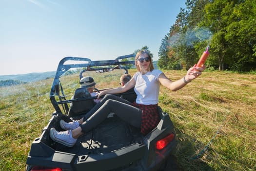 group of young happy excited people having fun enjoying beautiful sunny day holding colorful torches while driving a off road buggy car on mountain nature