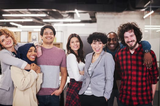portrait of young excited multiethnics business team of software developers standing and looking at camera while celebrating success at modern startup office