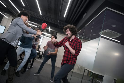multiethnics startup business team of software developers having fun while boxing at office,excited diverse employees laughing enjoying funny activity at work break, creative friendly workers playing game together