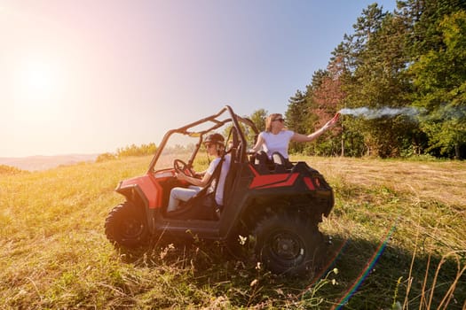 group of young happy excited people having fun enjoying beautiful sunny day holding colorful torches while driving a off road buggy car on mountain nature