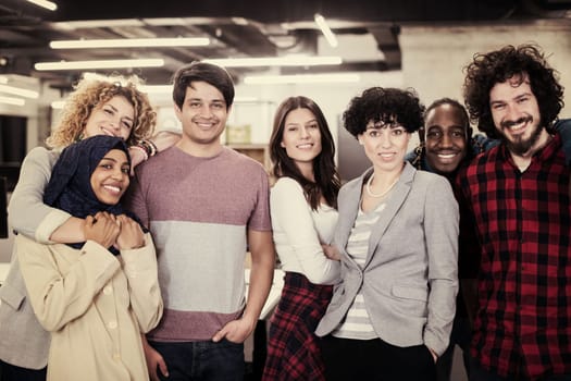 portrait of young excited multiethnics business team of software developers standing and looking at camera while celebrating success at modern startup office