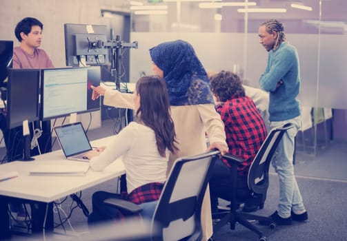young multiethnics business team of software developers working together using laptop computer while writing programming code at modern startup office