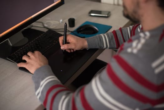 Young graphic designer working on a digital tablet and a computer