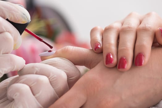 Woman hands receiving a manicure in beauty salon. Nail filing. Close up, selective focus.