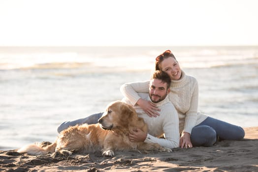 Couple With A Dog enjoying time  together On The Beach at autumn day