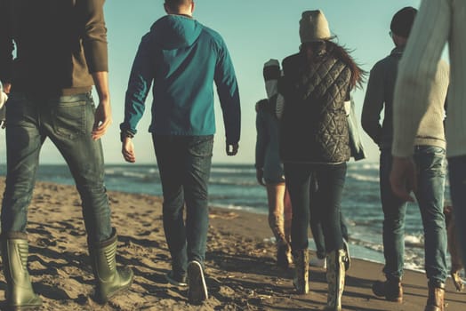 group of young friends spending day together running on the beach during autumn day