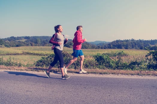 young couple enjoying in a healthy lifestyle while jogging along a country road, exercise and fitness concept