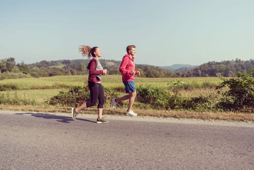 young couple enjoying in a healthy lifestyle while jogging along a country road, exercise and fitness concept