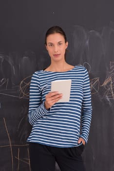 Happy young woman using tablet computer in front of chalk drawing board