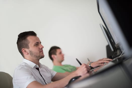 a group of young graphic designers working on a digital tablet and a computer