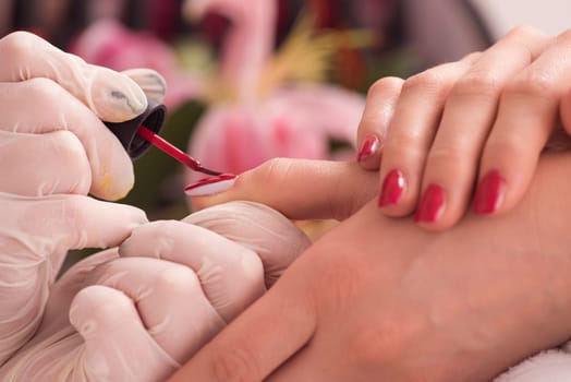 Woman hands receiving a manicure in beauty salon. Nail filing. Close up, selective focus.