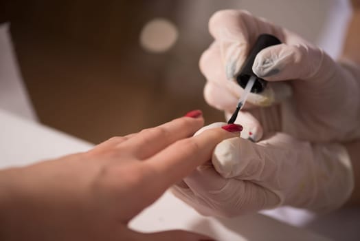Woman hands receiving a manicure in beauty salon. Nail filing. Close up, selective focus.
