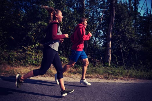 young couple enjoying in a healthy lifestyle while jogging along a country road, exercise and fitness concept