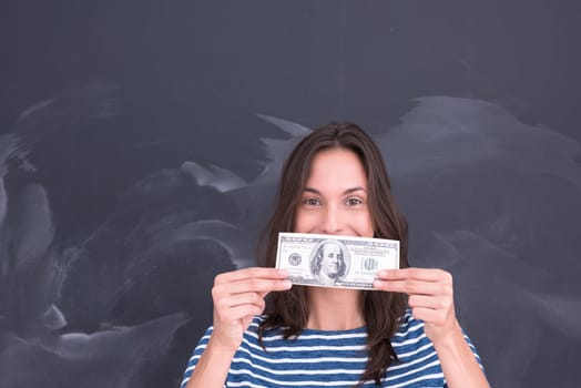 portrait of a young woman holding a banknote in front of chalk drawing board
