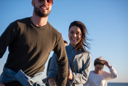 group of young friends spending day together running on the beach during autumn day