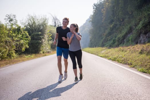 young couple enjoying in a healthy lifestyle while jogging along a country road, exercise and fitness concept