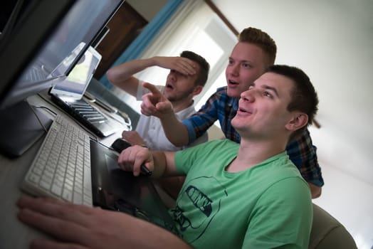 a group of young graphic designers working on a digital tablet and a computer