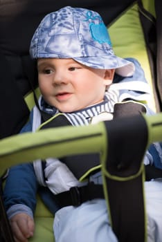 little and very beautiful baby boy sitting in the pram and waiting for mom