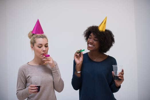 people and celebration concept  young multiethnics smiling women in party caps blowing to whistles