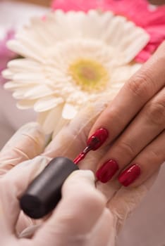 Woman hands receiving a manicure in beauty salon. Nail filing. Close up, selective focus.
