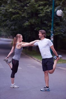 jogging couple warming up and stretching before running