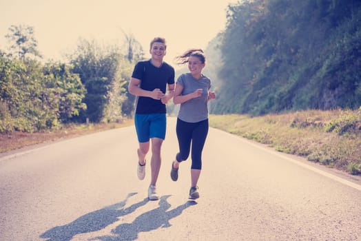 young couple enjoying in a healthy lifestyle while jogging along a country road, exercise and fitness concept