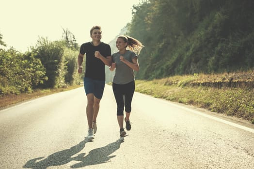 young couple enjoying in a healthy lifestyle while jogging along a country road, exercise and fitness concept