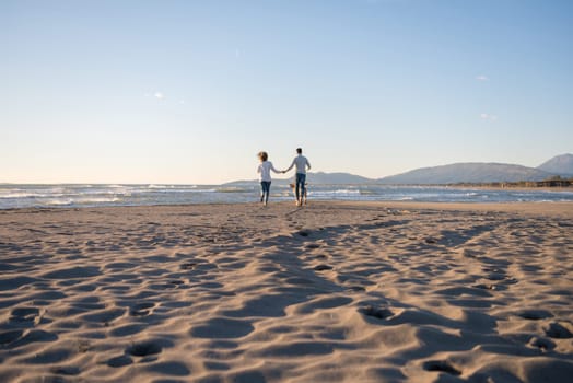 Couple Running On The Beach Holding Their Hands with dog On autmun day