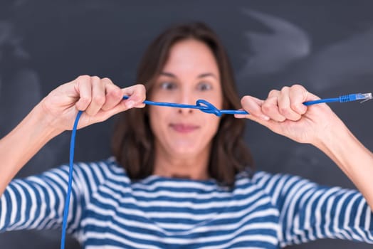 portrait of a young woman holding a internet cable in front of chalk drawing board