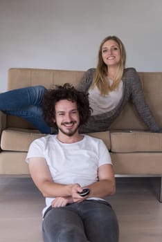 Young couple on the sofa watching television together in their luxury home